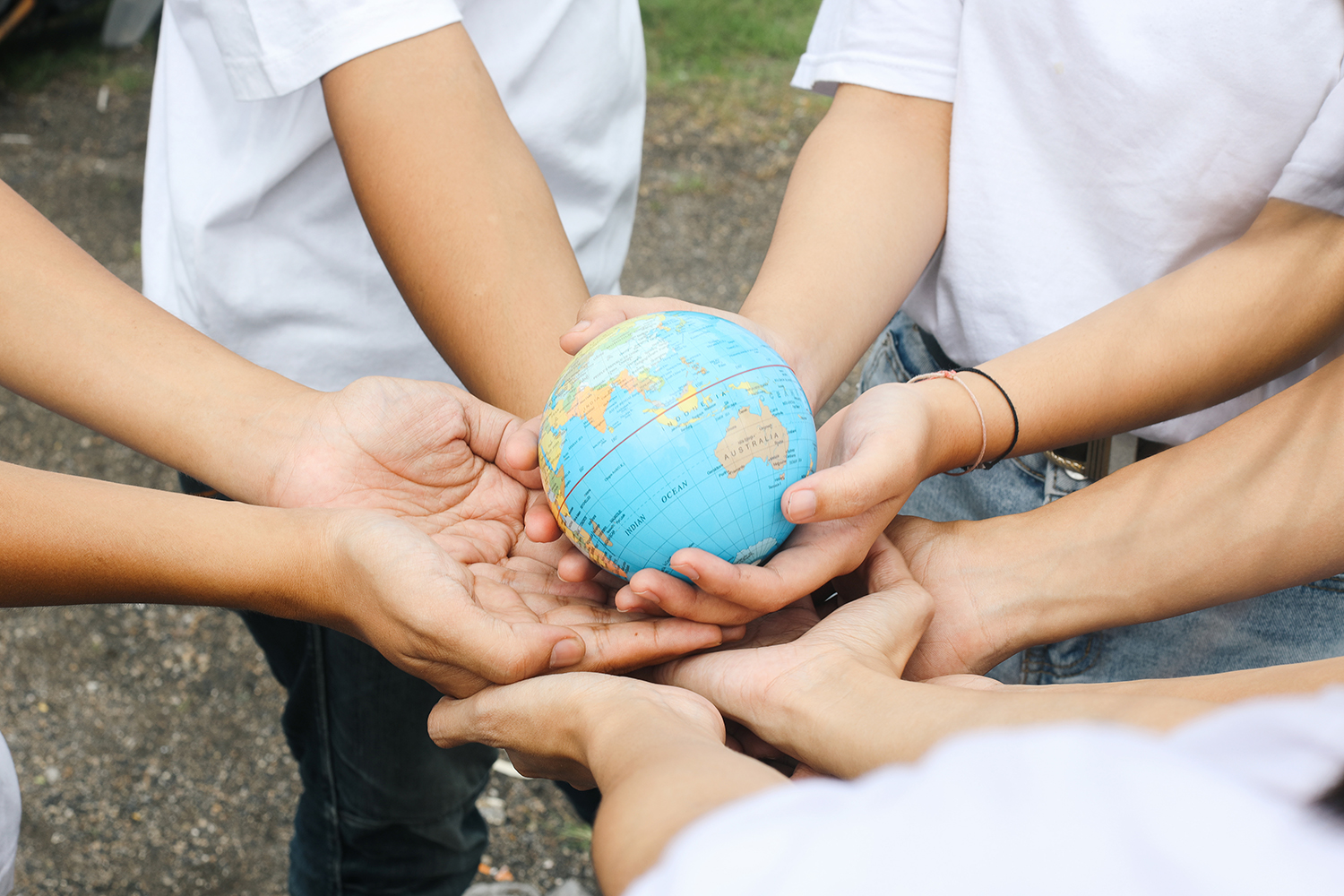 Image of children's hands in a circle holding a small globe.