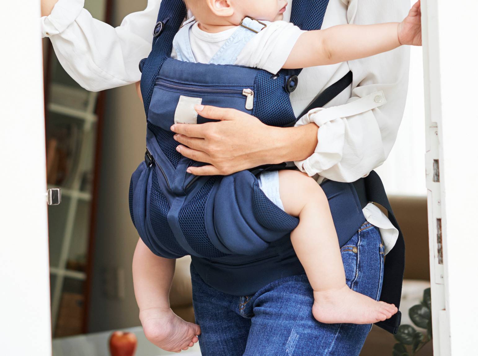 Photo of a baby in a blue baby carrier being worn on the front of a woman.